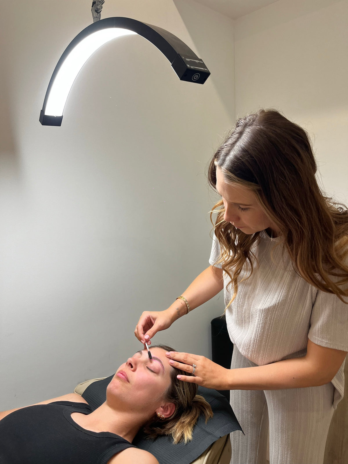 Annie brushing through a client’s brows under the arc lamp at Sœur. Beauty