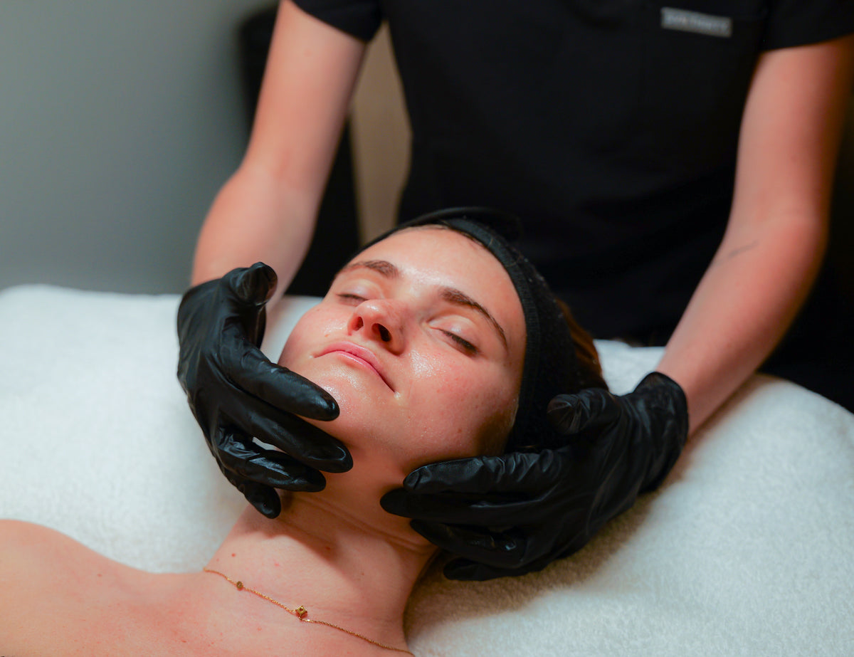 Gloved hands assessing a client's skin before treatment
