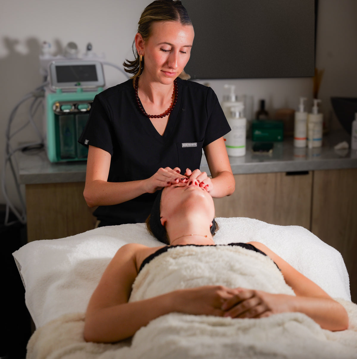 Kate in black scrubs working across a client's face during a facial
