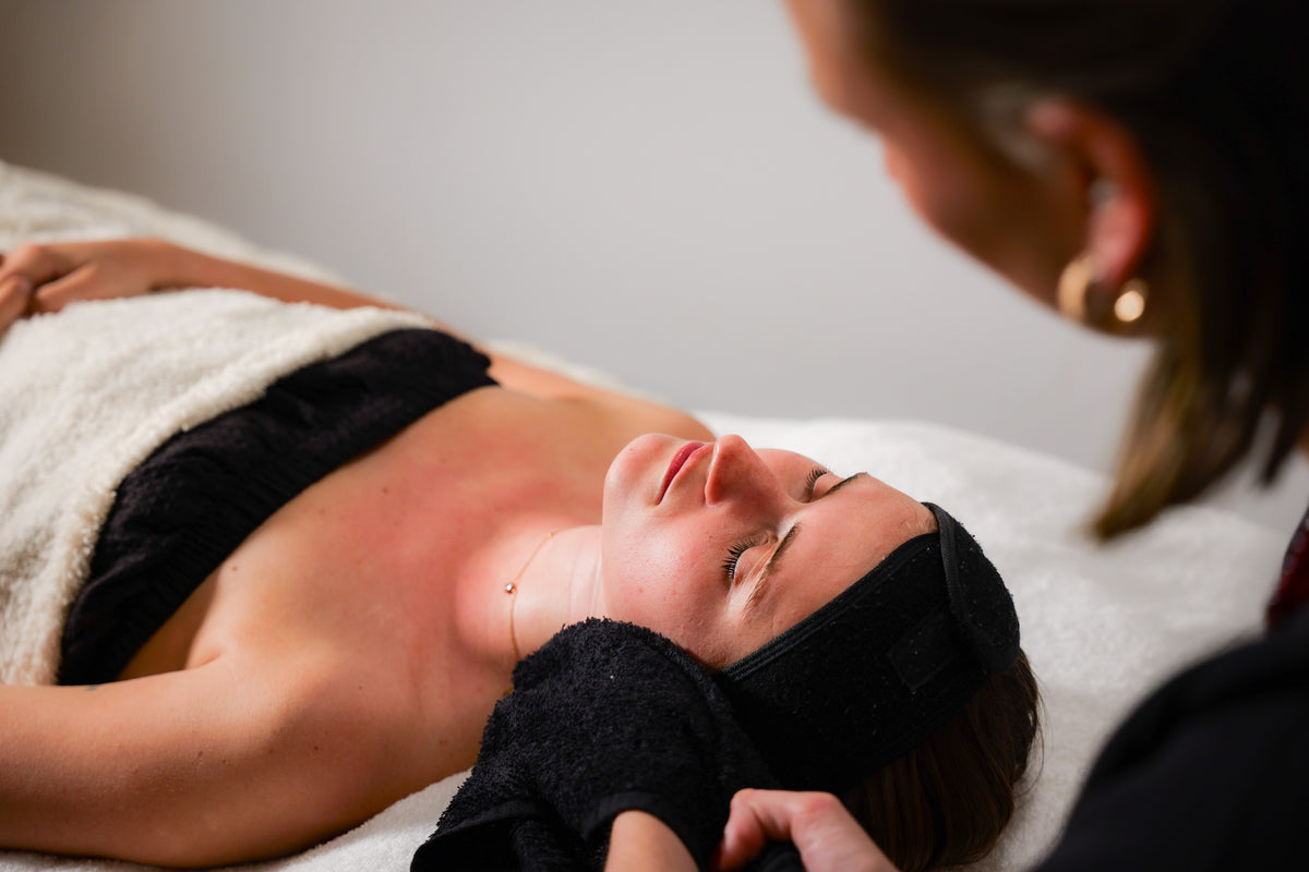 A client receiving a facial at Sœur. Skin, wrapped in a towel with her eyes closed