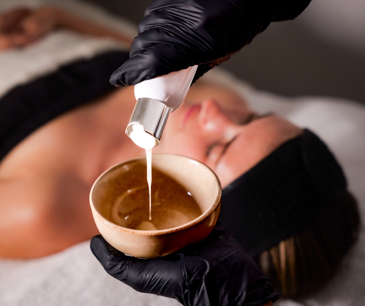 A facial treatment being mixed in a ceramic bowl above a client on the bed
