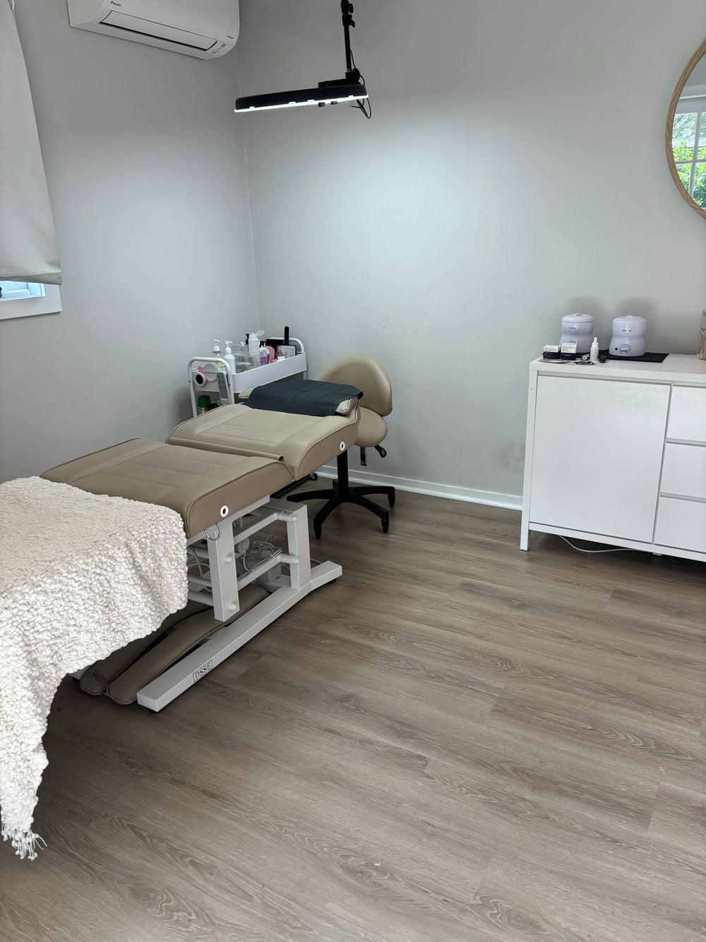 The renovated granny flat studio, a treatment bed under a task lamp in a clean, pale room