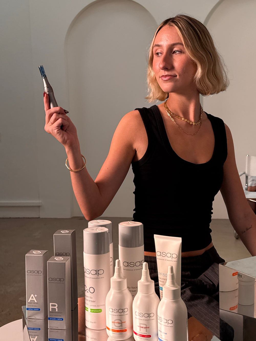 Kate in the Sœur. Skin clinic holding a skin-needling pen, ASAP products laid out in front of her